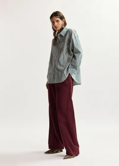 Woman wearing a striped shirt and burgundy pants on a white background