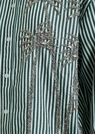 Striped shirt with decorative embellishments on a green and white background
