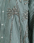 Striped shirt with decorative embellishments on a green and white background