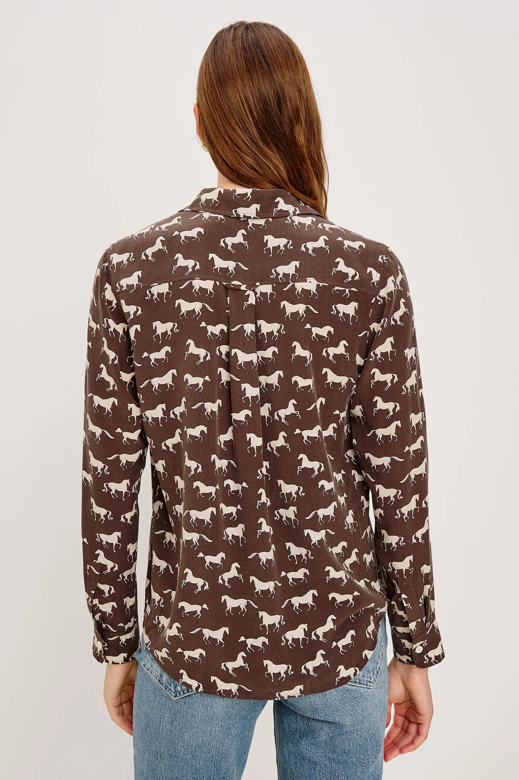Woman wearing a brown shirt with horse pattern on a white background back view