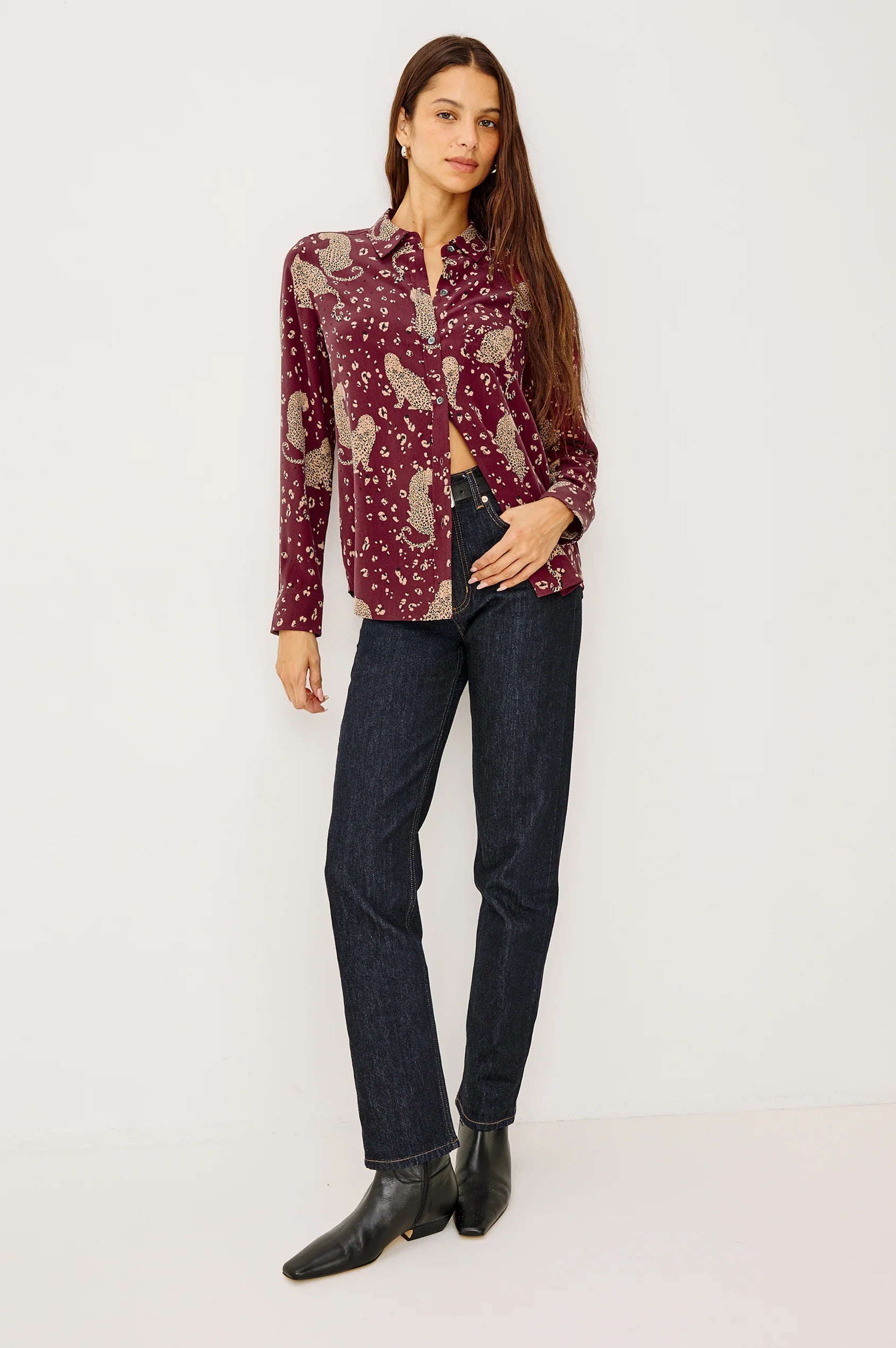 Woman wearing a patterned shirt and jeans on a white background