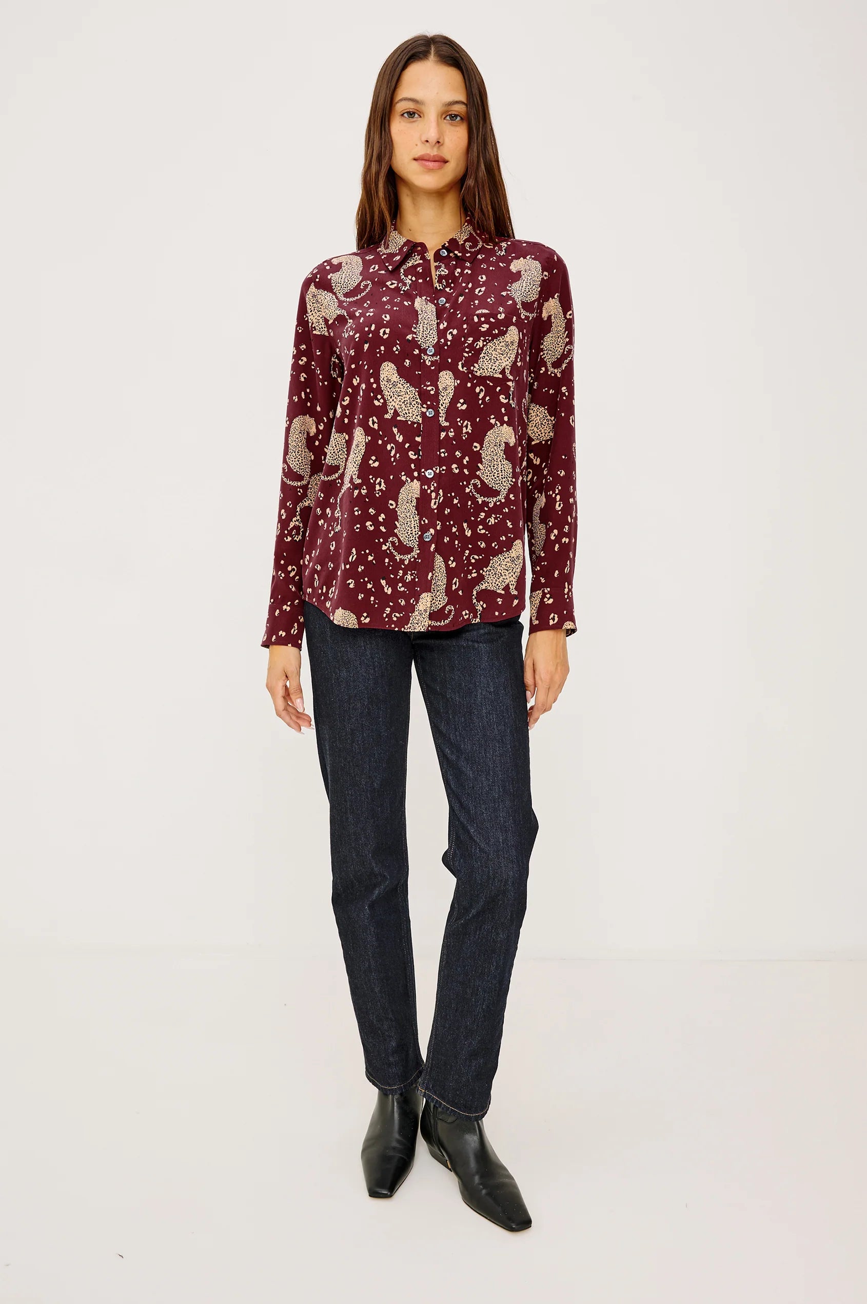 Woman wearing a patterned blouse and jeans on a white background
