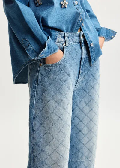 Person wearing a blue denim shirt and jeans on a white background