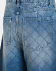 Close-up of blue jeans with a diamond pattern on the back pocket, featuring the brand 'Essential Antwerp'.