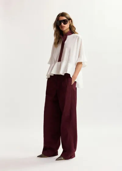 Woman wearing a white top and burgundy pants on a white background
