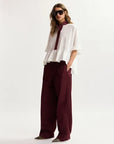 Woman wearing a white top and burgundy pants on a white background