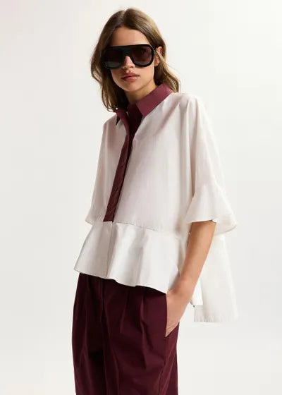 Woman wearing a white blouse with burgundy accents and sunglasses on a white background