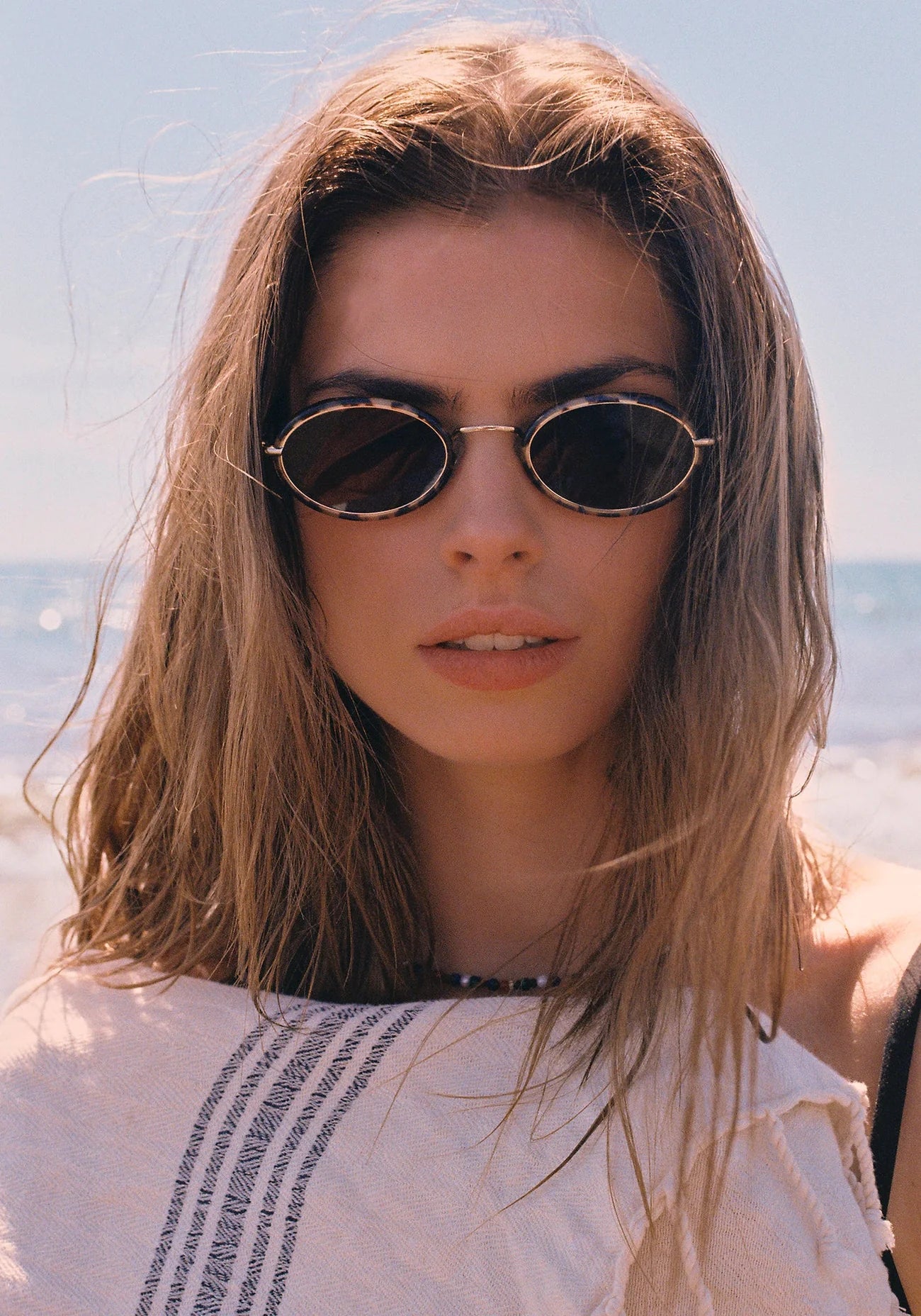 Woman wearing sunglasses with a blurred beach background