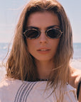 Woman wearing sunglasses with a blurred beach background