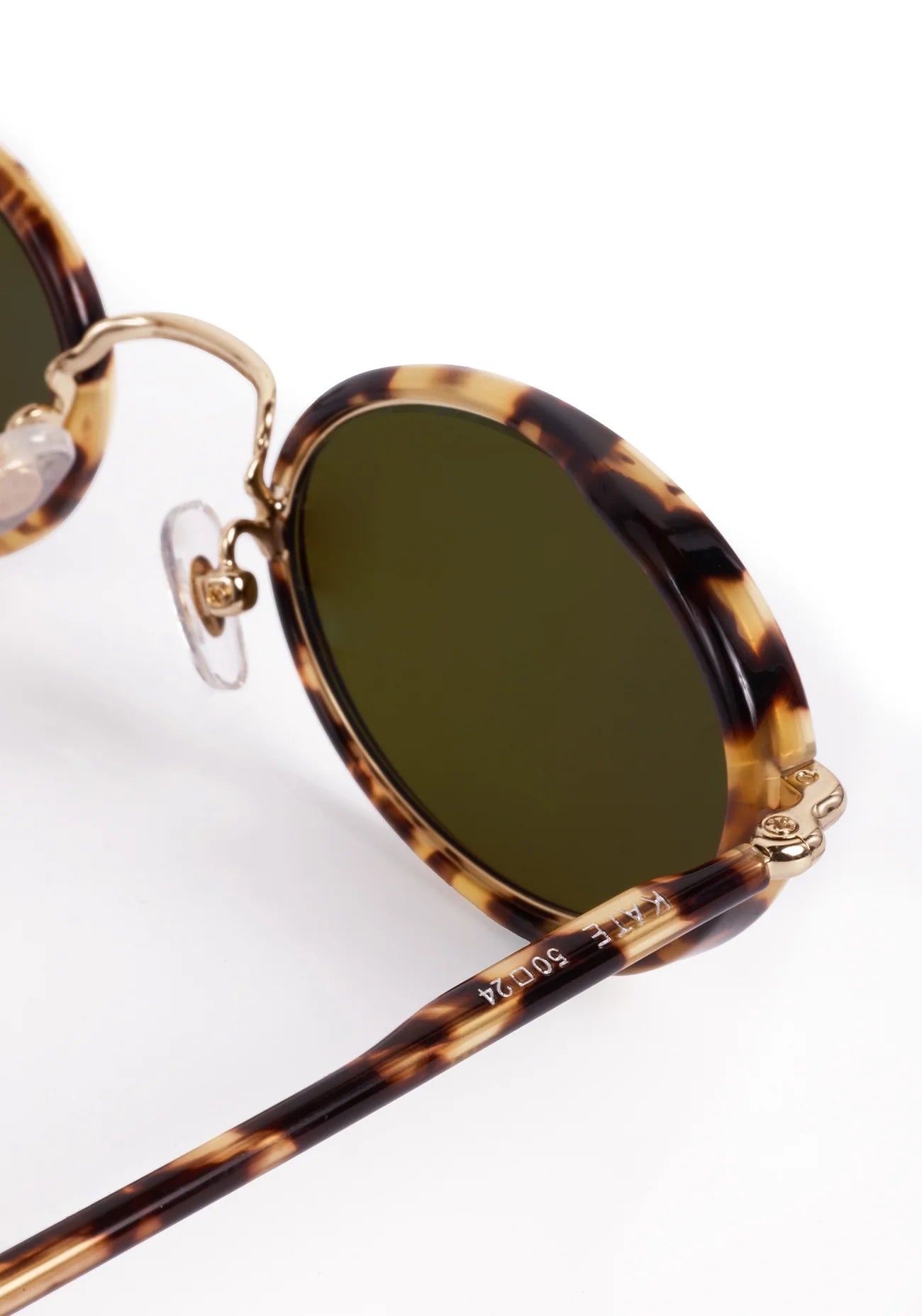 Sunglasses with tortoiseshell frame and green lenses on a white background