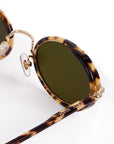 Sunglasses with tortoiseshell frame and green lenses on a white background