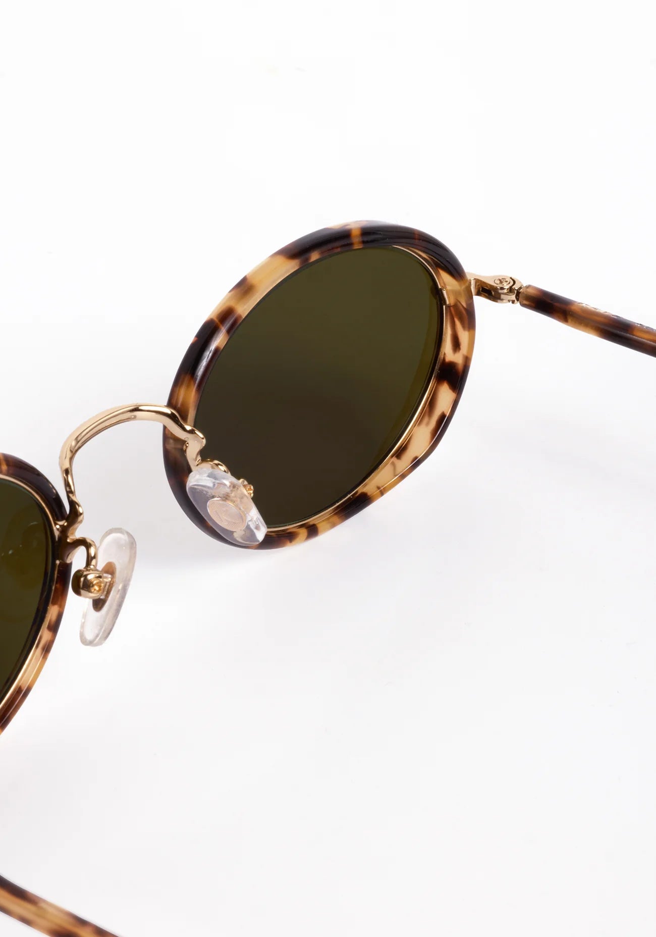 Sunglasses with tortoiseshell frame and green lenses on a white background