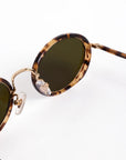 Sunglasses with tortoiseshell frame and green lenses on a white background
