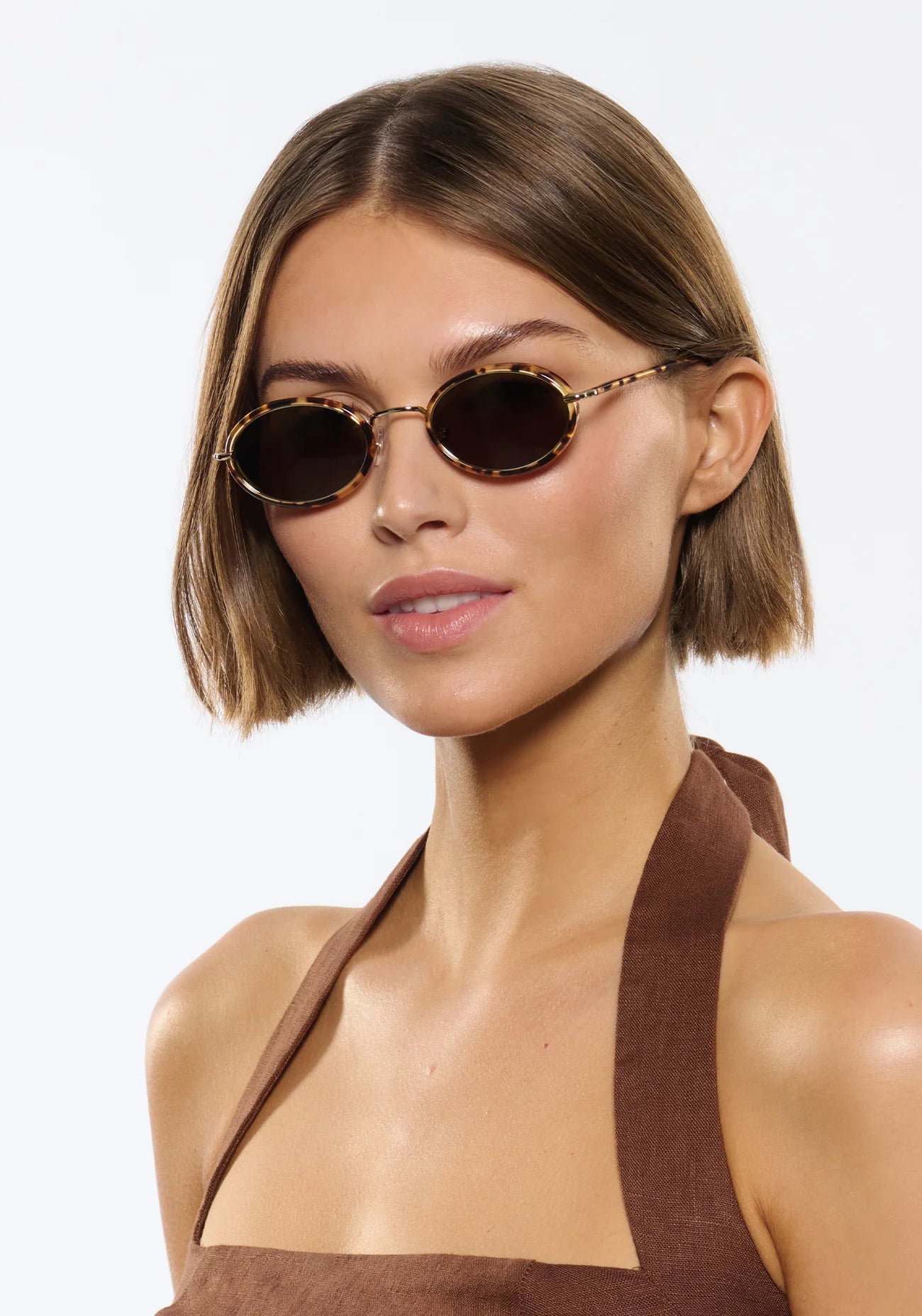 Woman wearing round sunglasses with a plain background