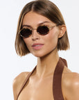 Woman wearing round sunglasses with a plain background