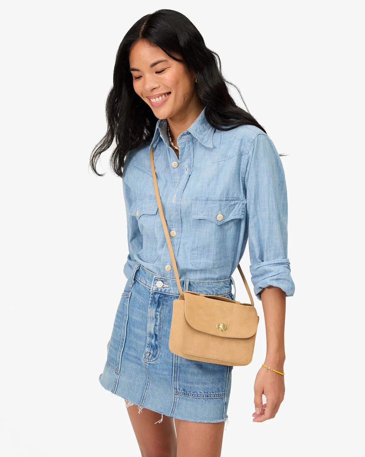 model wearing all denim with a tan crossbody bag on a white background