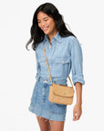 model wearing all denim with a tan crossbody bag on a white background