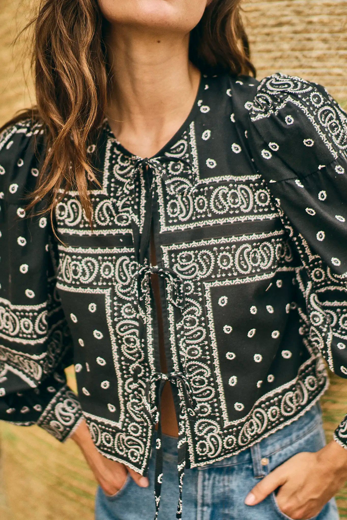 Person wearing a black bandana print shirt with a blurred background