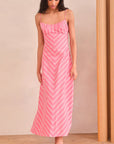 Woman wearing a pink and white striped dress against a beige wall.