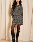 model wearing a zebra jacket top and mini skirt on a cream background 