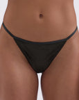 Black thong worn by a person on a white background