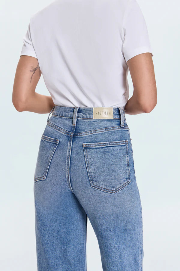 Person wearing blue jeans with a visible brand label on a white background