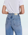 Person wearing blue jeans with a visible brand label on a white background