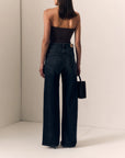 model wearing a strapless brown top with dark jeans on a cream background, back view 