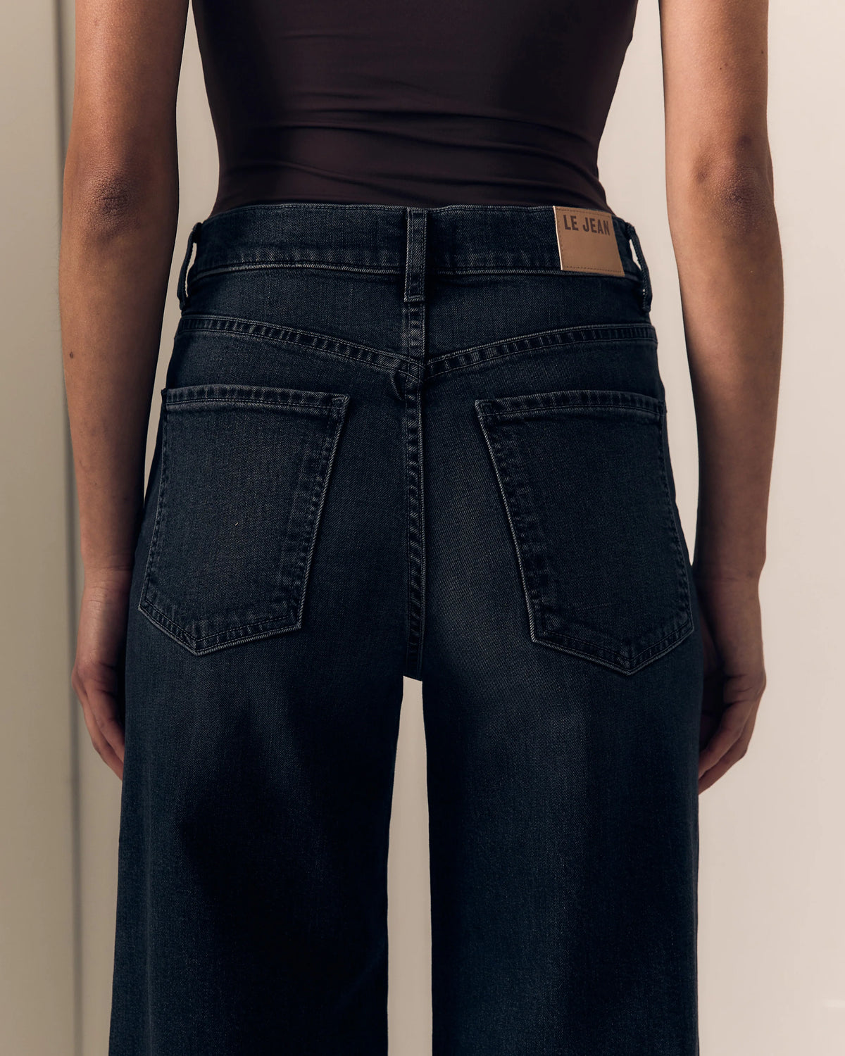 close up of the back of dark jeans on a model with a brown top 