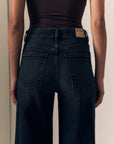close up of the back of dark jeans on a model with a brown top 