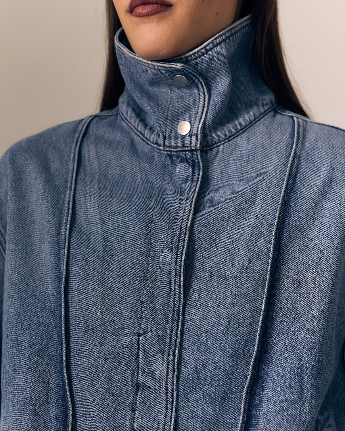 close up of a model wearing a denim jacket with the high collar 