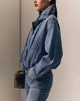 model wearing a denim jacket with jeans on a cream background, side view