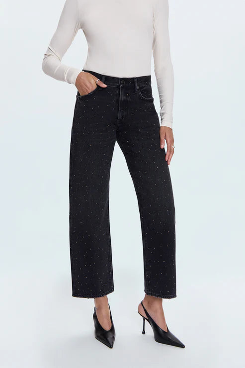 Person wearing black speckled jeans and a white top on a white background