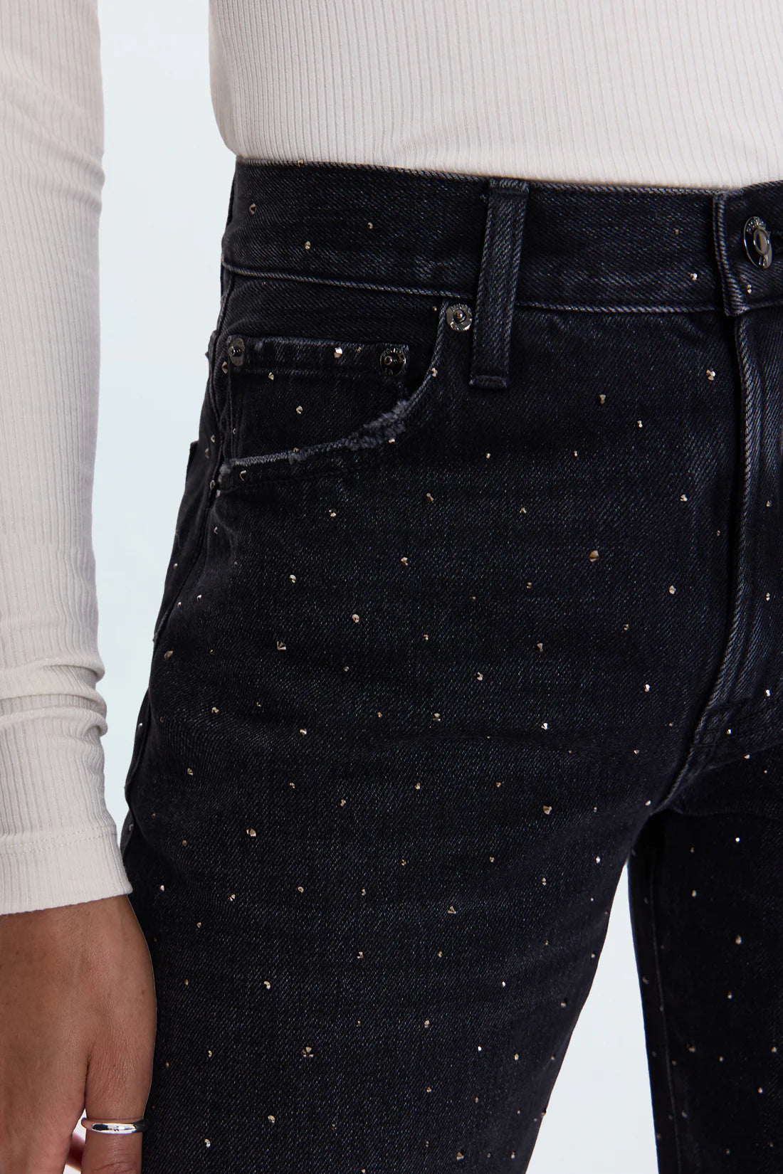 Black jeans with rhinestone embellishments worn by a person on a light gray background