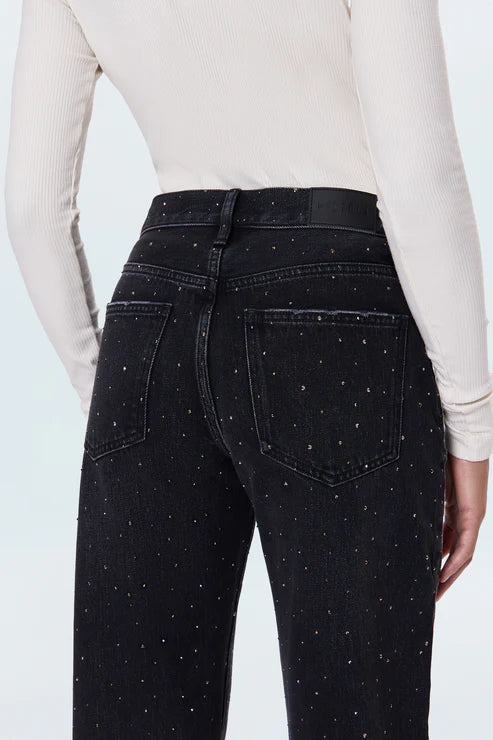 Black jeans with white speckles worn by a person on a light gray background