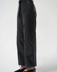 A model is shown from the waist down wearing black wide-leg pants with a drawstring waist and black pointed-toe mule heels, set against a plain light gray studio background.