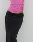 Person wearing a pink top and black skirt against a white background