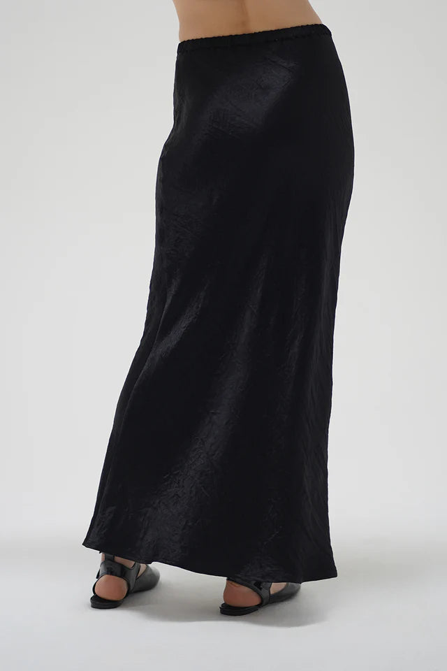 Black satin skirt worn by a person on a white background