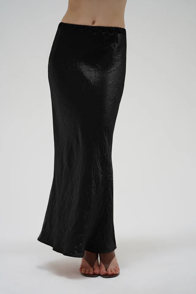 Black satin skirt worn by a person on a white background
