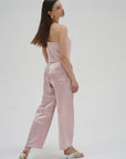 Woman wearing a pink strapless top and pants on a white background