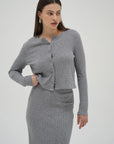 Woman wearing a gray cardigan and skirt set on a white background