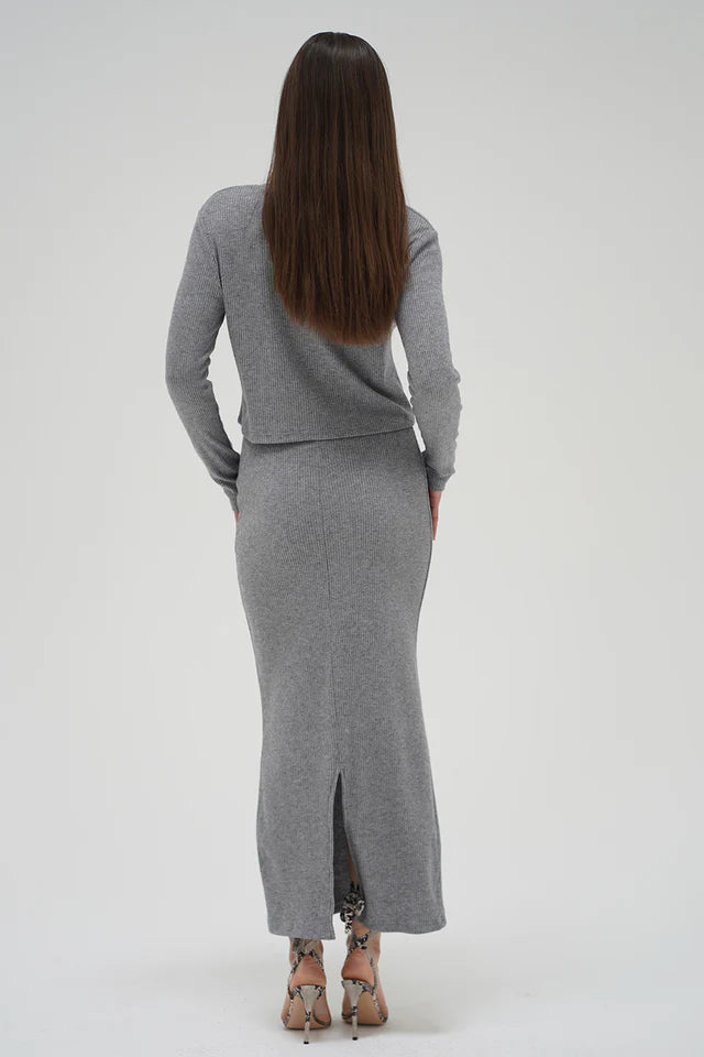 Woman wearing a gray knit outfit with a skirt on a white background