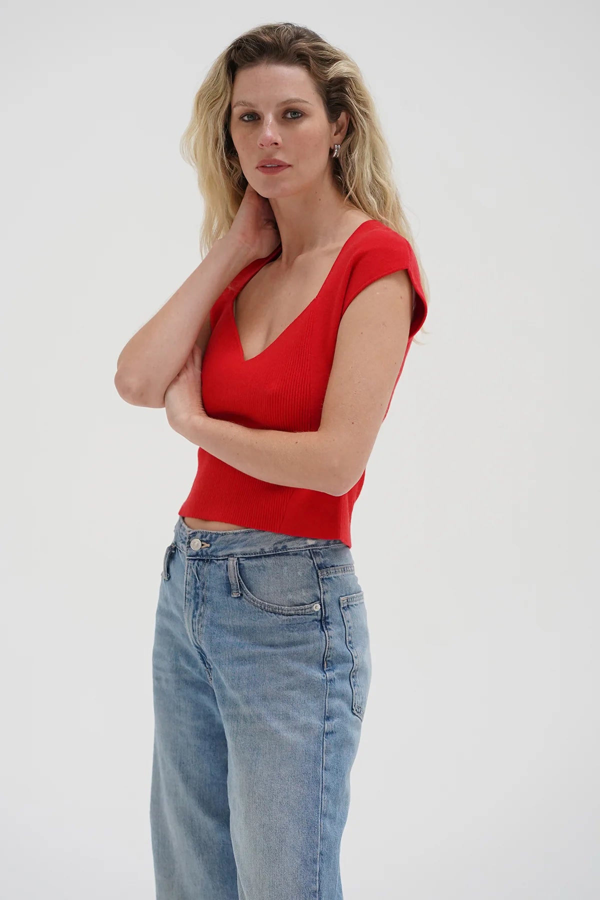 Woman wearing a red top and blue jeans on a white background