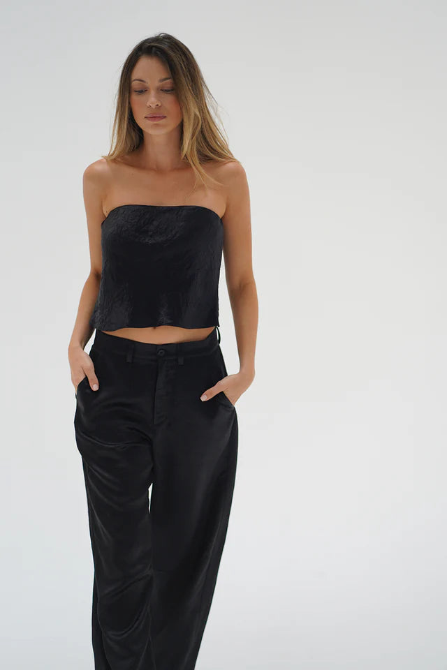 Woman wearing a black strapless top and black pants on a white background