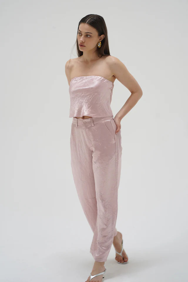 Woman wearing a pink strapless top and pants on a white background