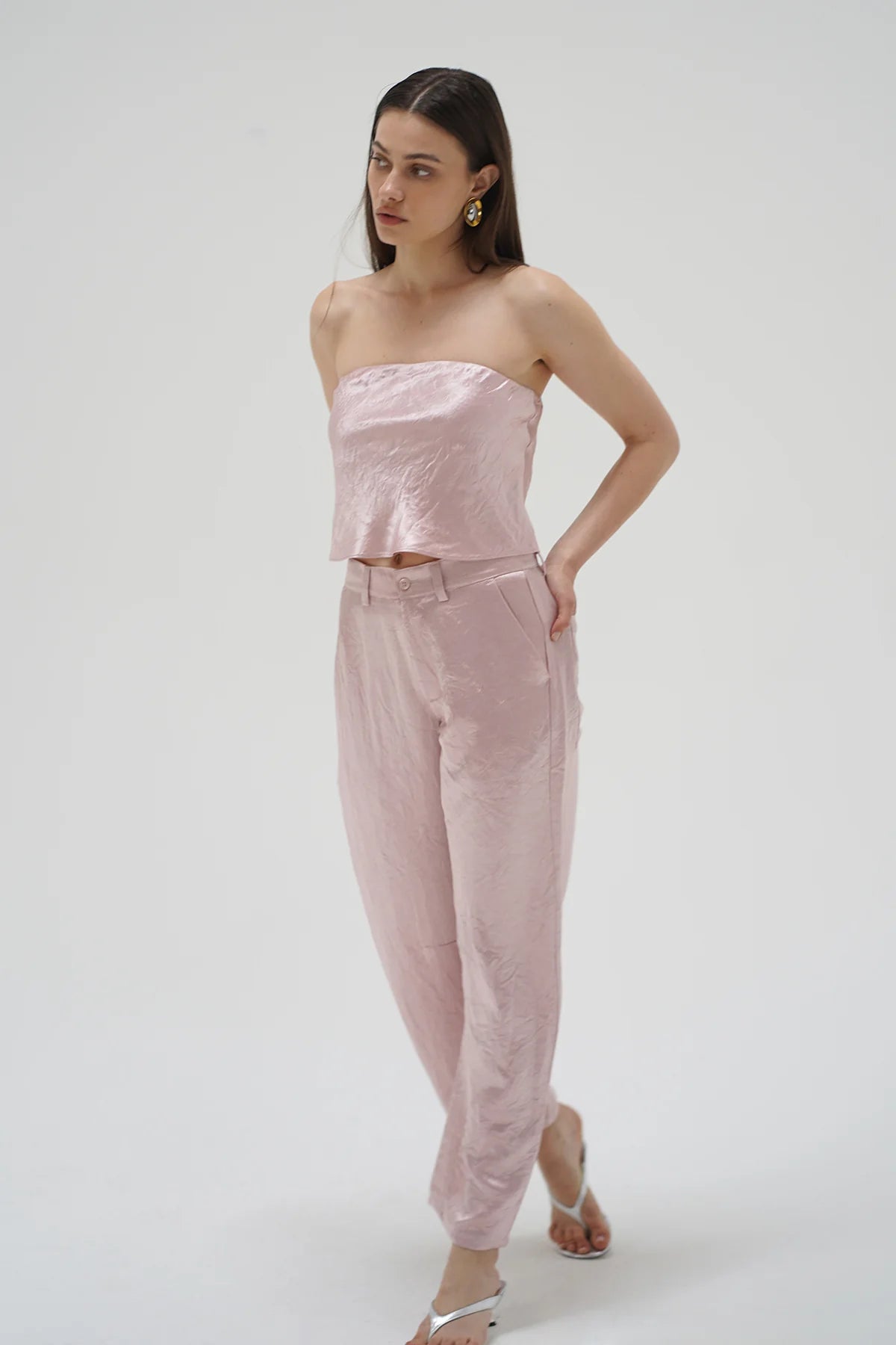Woman wearing a pink strapless top and pants on a white background