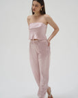 Woman wearing a pink strapless top and pants on a white background