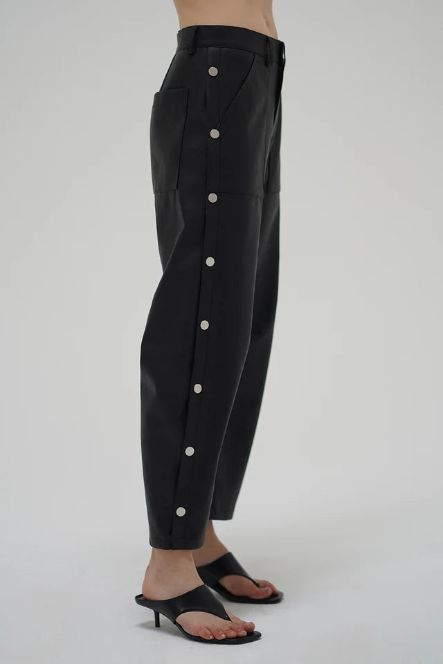 Black pants with white buttons on a gray background side view