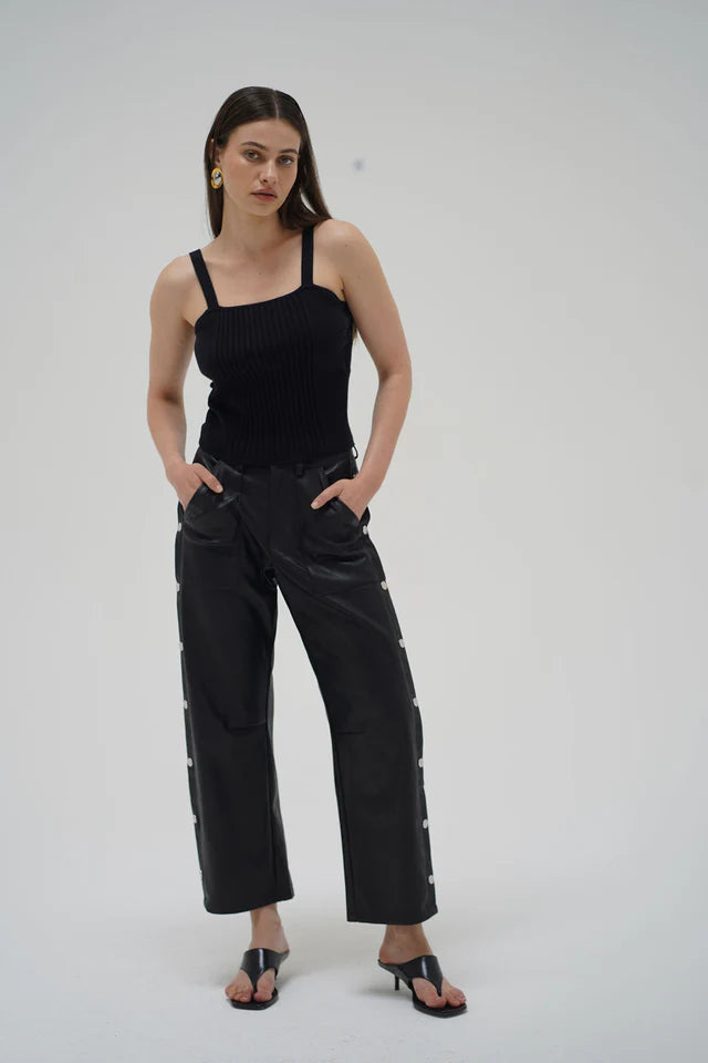 Woman wearing a black sleeveless top and black pants on a white background front view