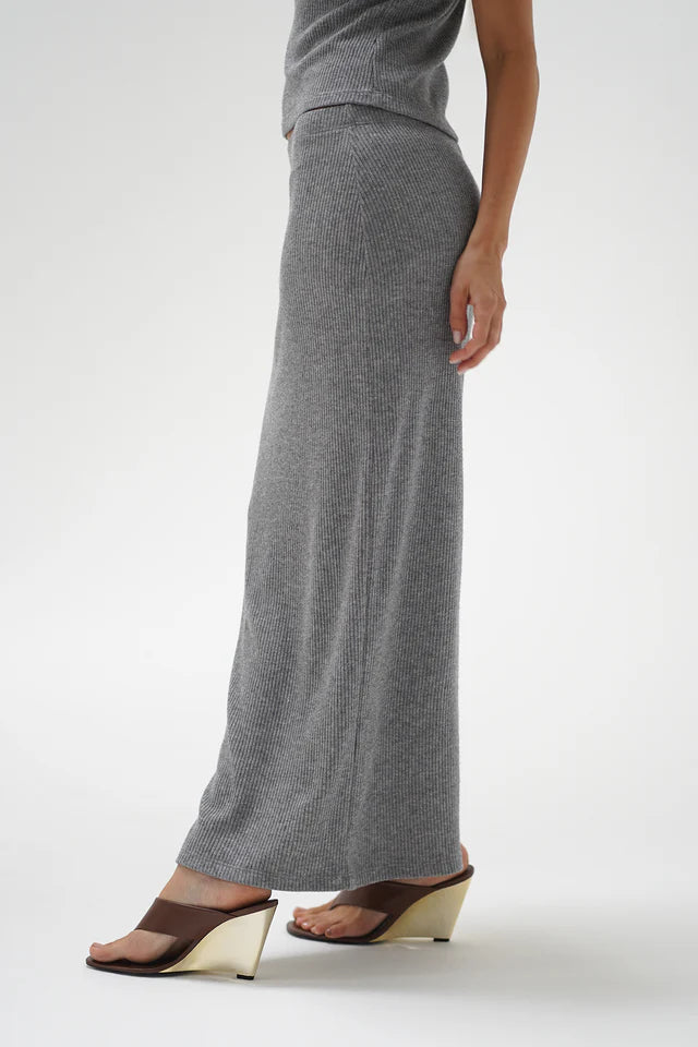 Person wearing a long gray skirt on a white background